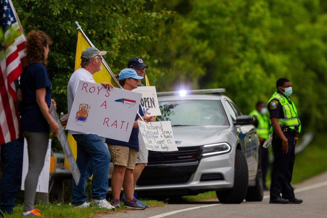 Protesters hold signs outside the NC Emergency Operations Center in Raleigh where Gov. Roy Cooper’s delivered his coronavirus response briefing Tuesday, May 5, 2020.