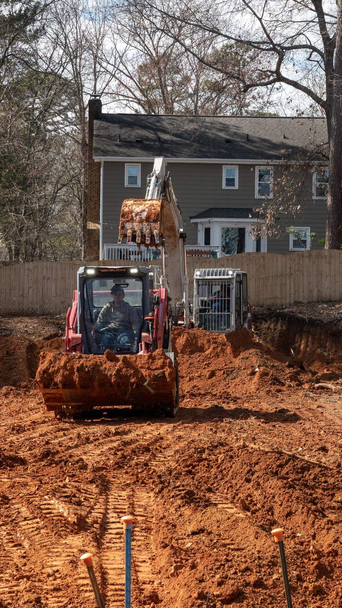 A compact track loader and a back hoe work the lot after the original house was torn down at 7817 Audubon Drive in North Raleigh, NC Feb. 23, 2026.