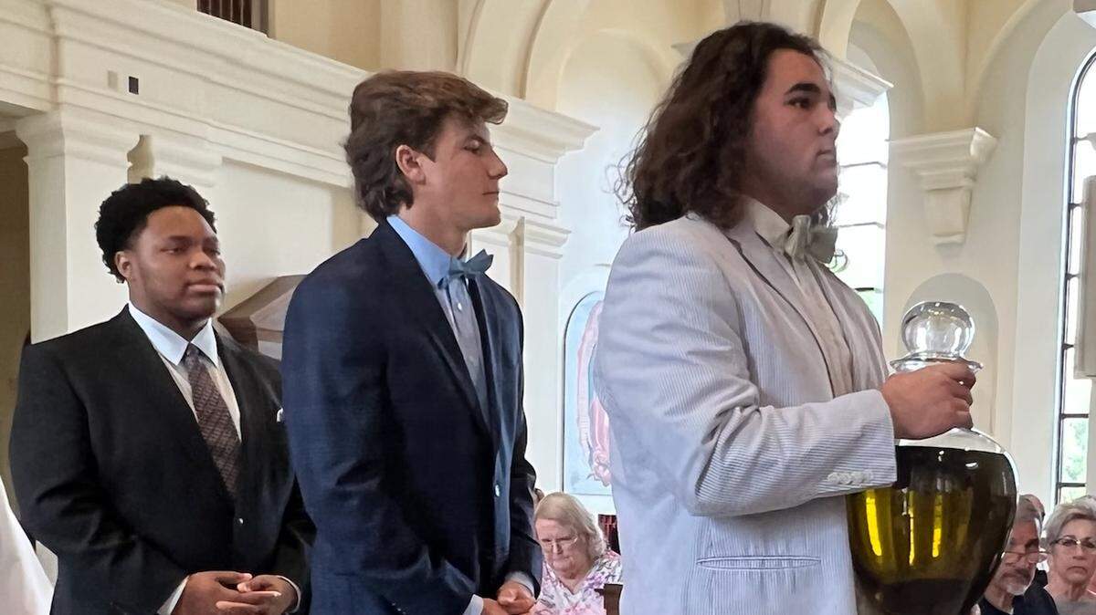 Joey Olivieri, right, followed by Ethan Grace, center, and Jonathan Ward, members of the 2021 Cardinal Gibbons state championship football team, were among Tuesday’s Chrism Mass liturgical ministers at the Diocese of Raleigh Chrism Mass on Tuesday, April 12, at Holy Name of Jesus Cathedral in Raleigh.