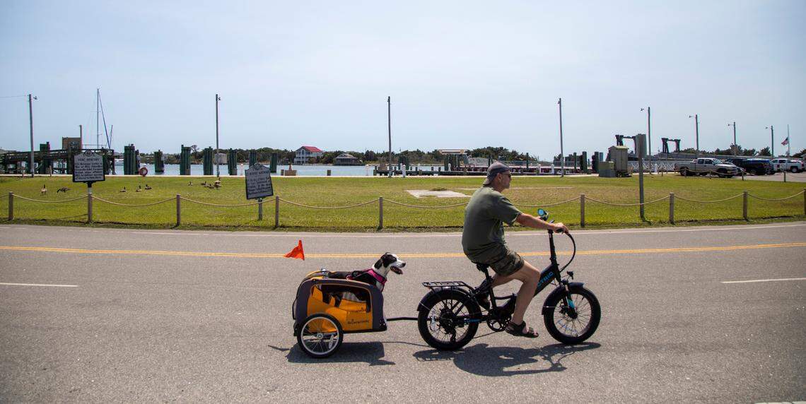 A man pulls his dog by bicycle on NC-12 in Ocracoke Wednesday, May 18, 2022. Bicycles and golf carts are the main modes of transportation on the island.