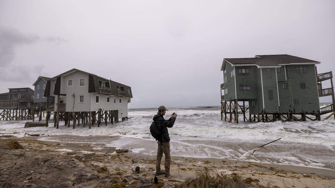 Professional storm chaser Noah Junot records video as rough surf threatens beach homes during high tide Saturday, Oct. 11, 2025, in Buxton as a nor’easter approaches the North Carolina coast. Nine homes in the community have collapsed into the Atlantic Ocean since mid-September.