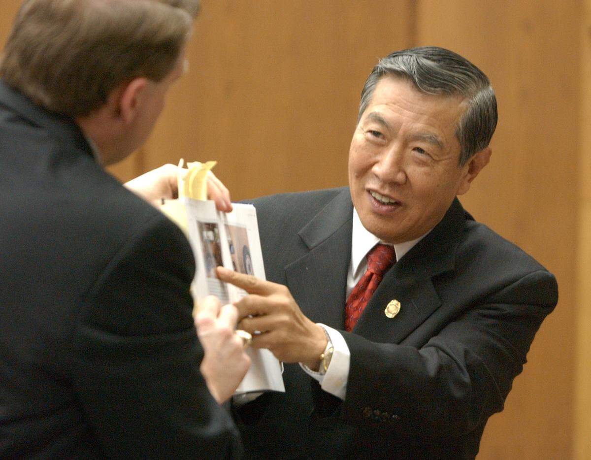 Forensic scientist and blood spatter expert Henry C. Lee right, indicates to the jury, at right out of photograph, an instance of when Lee used the stringing method in his crime scene studies. At left is prosecutor Jim Hardin, holding Lee's forensics book for the jury during the second day of cross-examination for Lee at the Michael Peterson murder trial in September 2003.