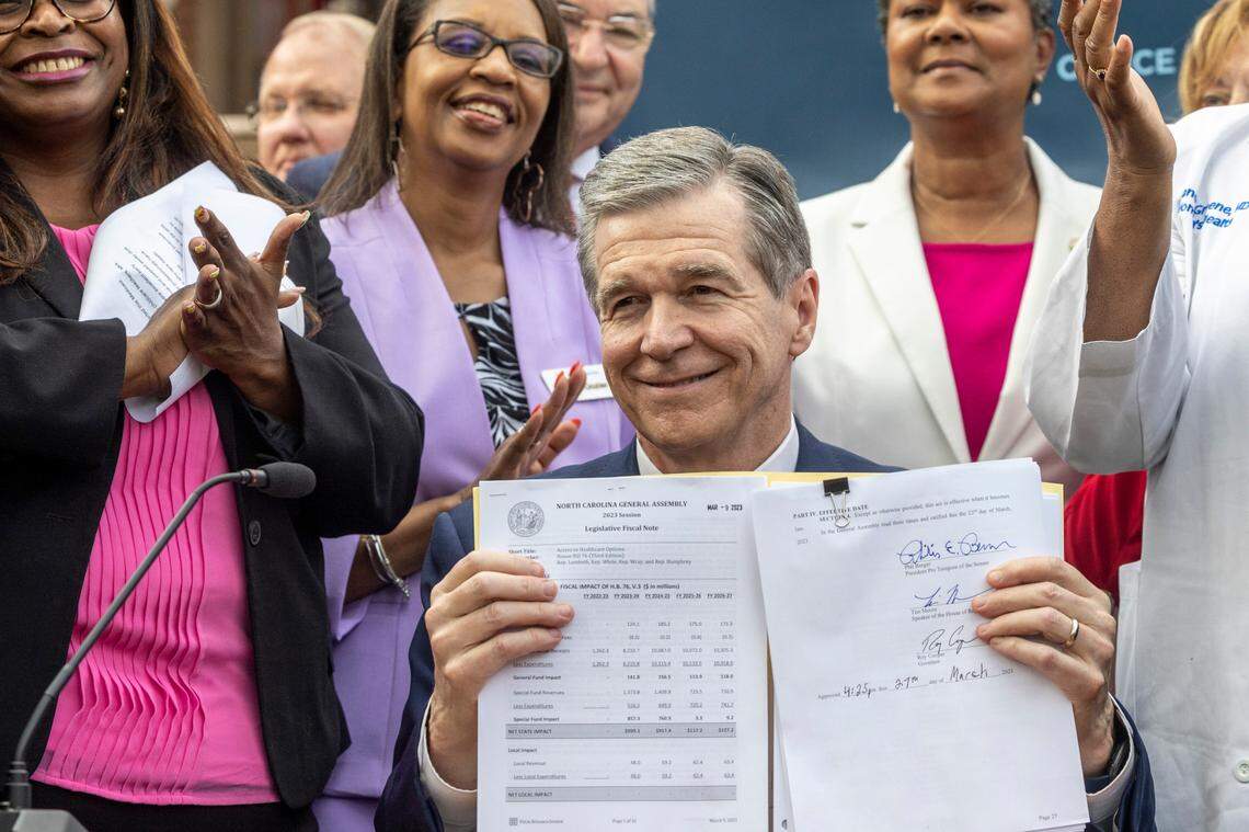 Gov. Roy Cooper holds up the Medicaid expansion bill after signing it into law during a ceremony at the Executive Mansion Monday, March 27, 2023.