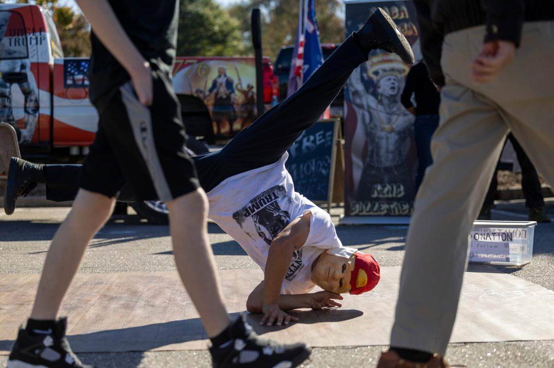 A man breakdances for tips as supporters of former President Donald Trump gather outside Minges Coliseum in Greenville prior to a rally on Monday, Oct. 21, 2024. With two weeks until Election Day, Trump went on a three-city tour, in which Trump will also see the destruction caused by Hurricane Helene in Asheville and speak at a faith conference in Concord.