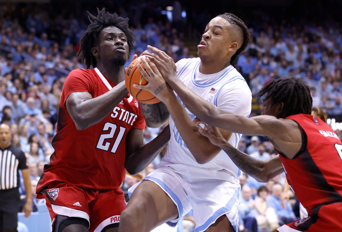 North Carolina’s Armando Bacot (5) drives as N.C. State’s Ebenezer Dowuona (21) and Terquavion Smith (0) defend against during the first half of N.C. State’s game against UNC at the Smith Center in Chapel Hill, N.C., Saturday, Jan. 21, 2023.
