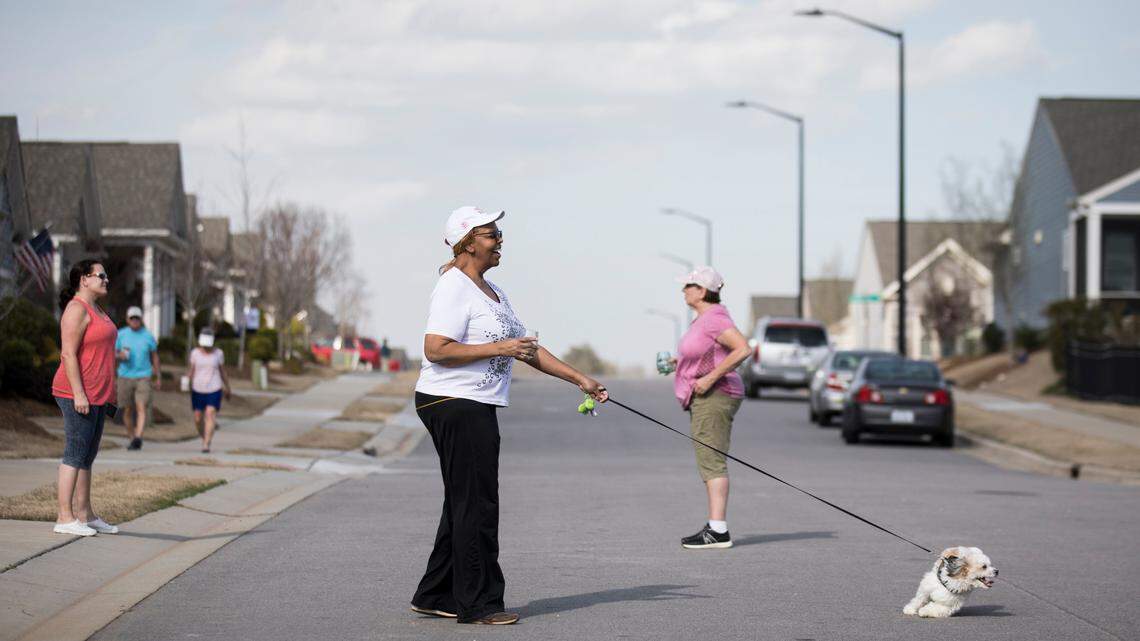Christie Pearson is tugged along by her dog Shadow during a neighborhood social distancing happy hour in Carolina Arbors in Durham, NC on Friday, March 20, 2020.