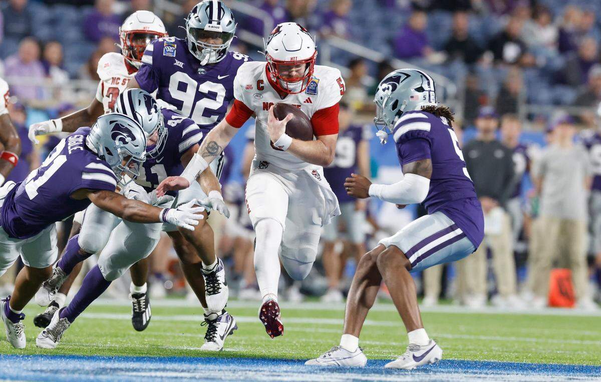 N.C. State quarterback Brennan Armstrong (5) gains yards while pursued by Kansas State defenders during the first half of N.C. State’s game against Kansas State in the Pop-Tarts Bowl at Camping World Stadium in Orlando, Fla., Thursday, Dec. 28, 2023.