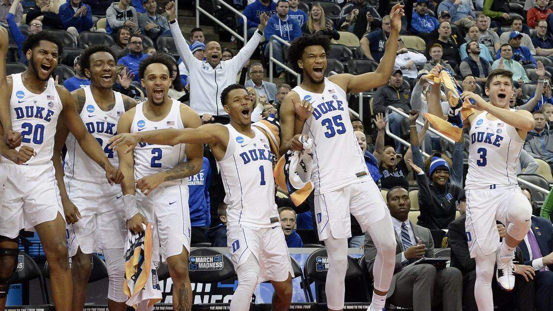 The Duke bench explodes as reserve forward Justin Robinson (50) dunks the ball in the closing seconds of their win over Iona.