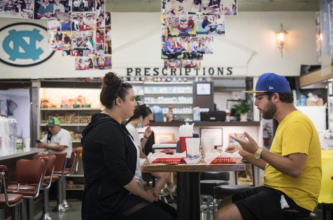 Kira Abuchowski, left, and Joseph Partin, right, have a meal at Sutton’s Drug Store in Chapel Hill, N.C. on Thursday, Aug. 27, 2020. Like many other small business across the country, Sutton’s has struggled during the coronavirus pandemic. After 97 years of business, owner Don Pinney hopes they can still make it to the big 100.