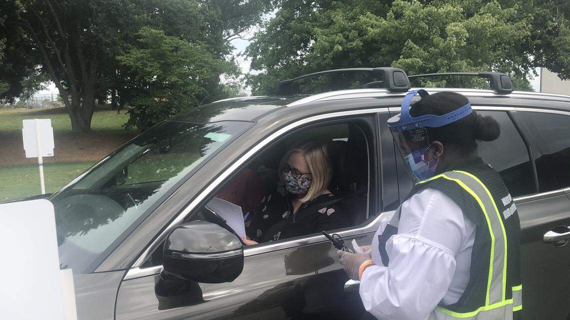 School board member Heather Scott (left) fills out paperwork to run for re-election given to her by Taylor Williams, a Wake County Board of Elections voter registration supervisor, on June 8, 2020. Due to COVID-19, the Wake County Board of Elections is offering curbside registration for candidates at his operations center in Raleigh, N.C.