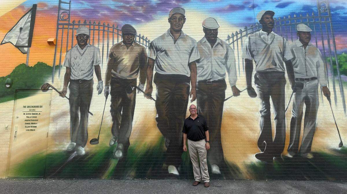 Chris Simkins stands in front of a new mural depicting his father, civil rights activist Dr. George Simkins, and the rest of the Greensboro Six. This group is credited with integrating Greensboro’s Gillespie Golf Course in an act of civil disobedience in 1955. The activists were honored with the unveiling of a massive mural at Gillespie on Monday, Aug. 5, 2024, ahead of the Wyndham Championship, which is taking place in Greensboro this week.