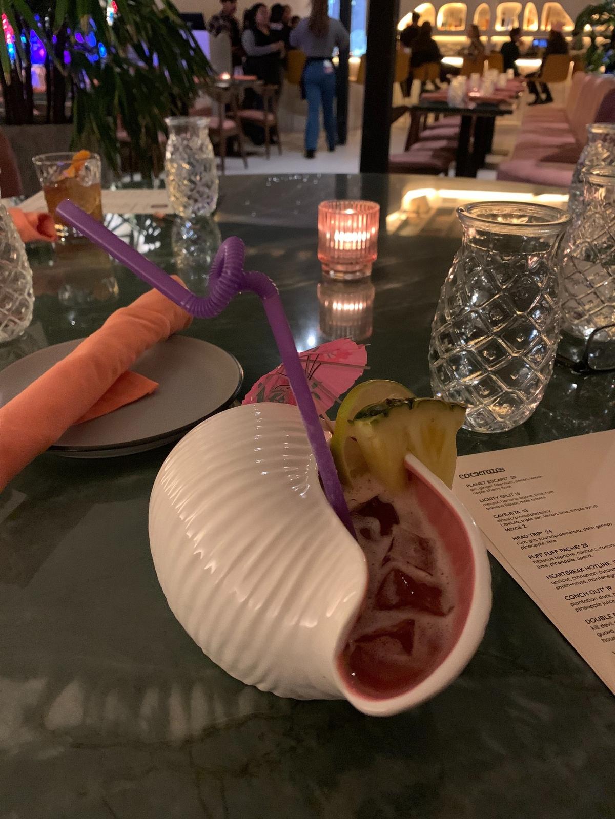 The cocktail list of tiki drinks as Aaktun includes the “Conch Out,” a vibrant punch served in a porcelain conch shell.