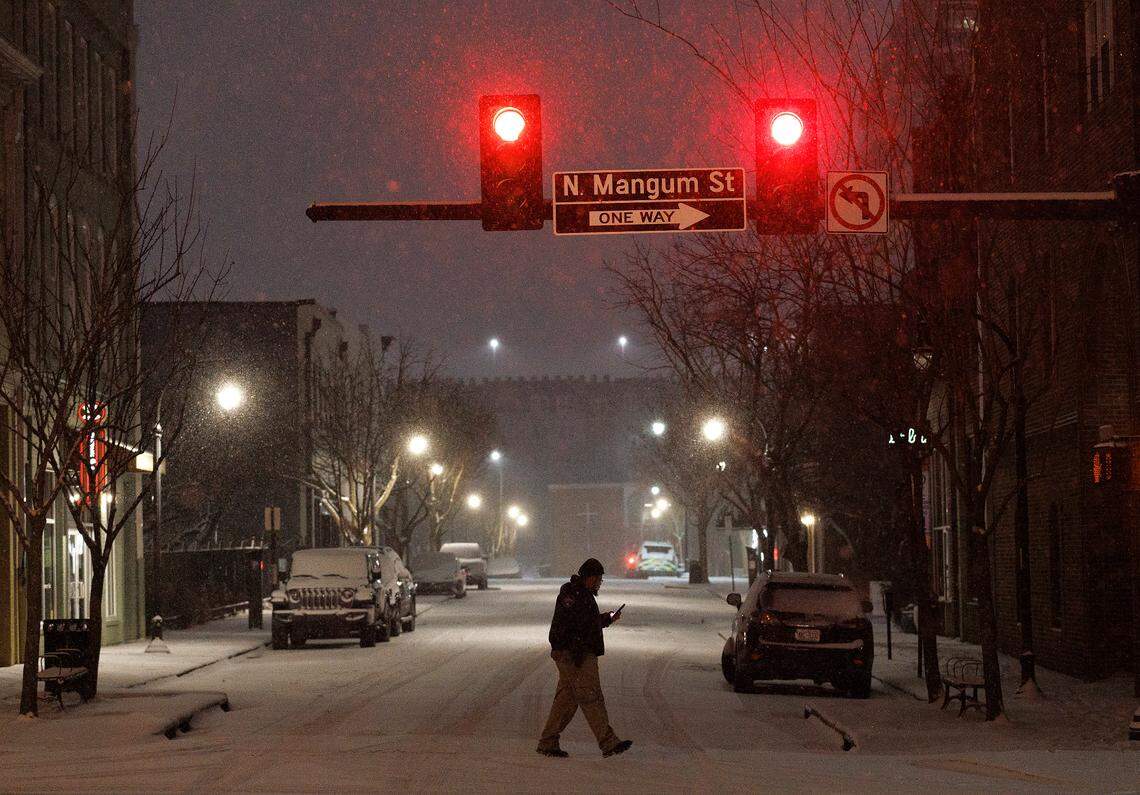 A person walks along a snow-covered street in downtown Durham, N.C. on Tuesday, Jan. 21, 2025.
