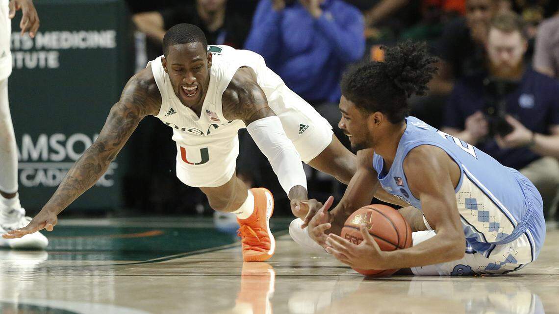 Miami guard Zach Johnson, left, dives for the ball against North Carolina guard Coby White during the second half of an NCAA college basketball game on Saturday, Jan. 19, 2019, in Coral Gables, Fla.
