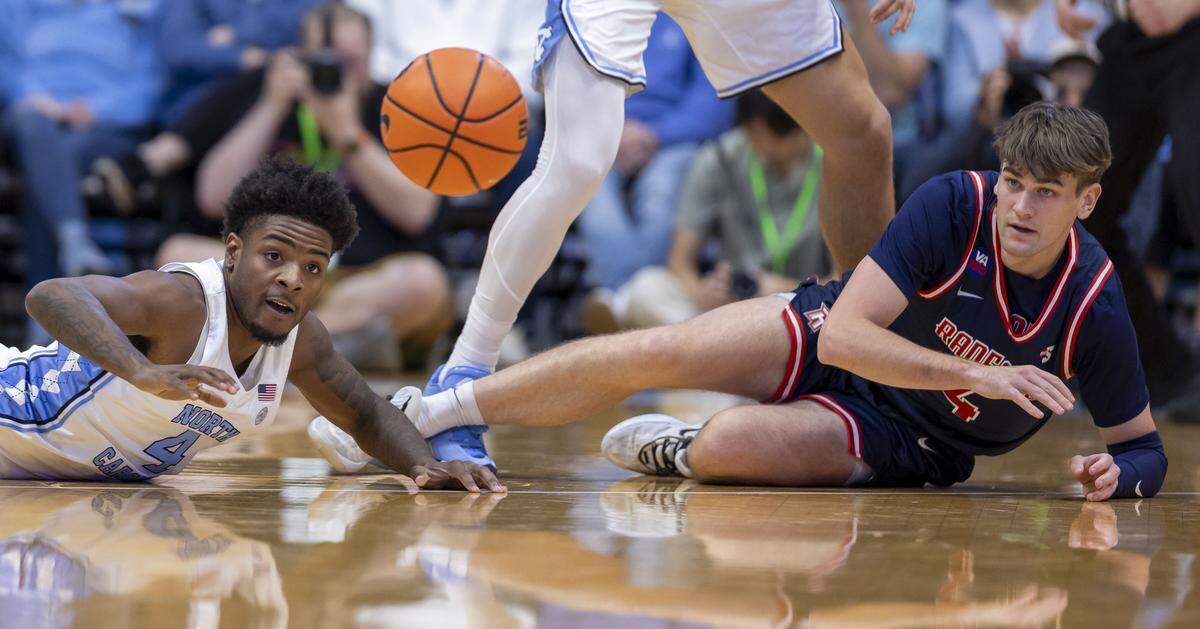 North Carolina guard Jaydon Young (4) and Radford guard Brennan Rigsby Jr. (4) hit the court after a loose ball in the first half on Tuesday, November 11, 2025 at the Smith Center in Chapel Hill, N.C.