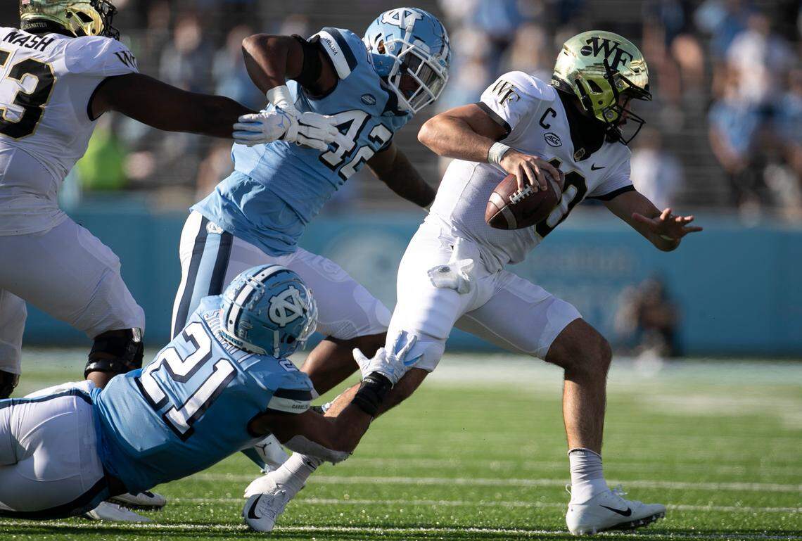 Wake Forest quarterback Sam Hartman (10) scrambles away from North Carolina linebacker Chazz Surratt (21) in the third quarter at Kenan Stadium on Saturday, November 14, 2020 in Chapel Hill, N.C.