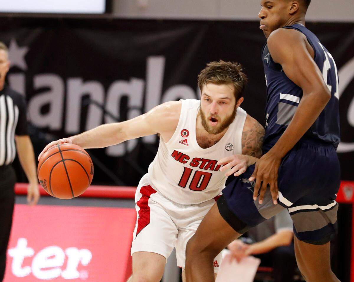 N.C. State’s Braxton Beverly (10) drives around North Florida’s Jonathan Aybar (21) during the first half of N.C. State’s game against North Florida in the Mako Medical Wolfpack Invitational at Reynolds Coliseum in Raleigh, N.C., Friday, Nov. 27, 2020.