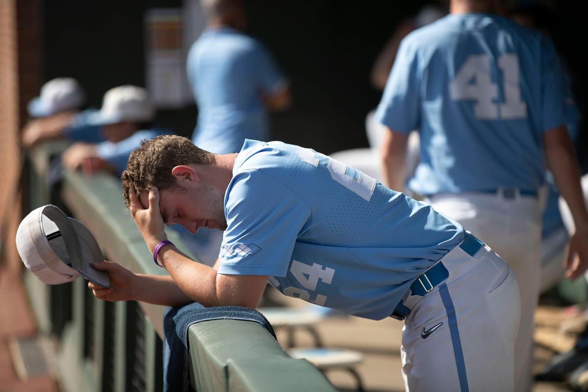 North Carolina pitcher Hansen Butler (24) hangs his head in the Tar Heels’ dugout as the Auburn Tigers celebrate their 14-7 victory in the NCAA Super Regional on Monday, June 10, 2019 at Boshamer Stadium in Chapel Hill, N.C. Butler pitched in the first inning and gave up 6 runs as Auburn ran up a 13-0 lead in the first inning.