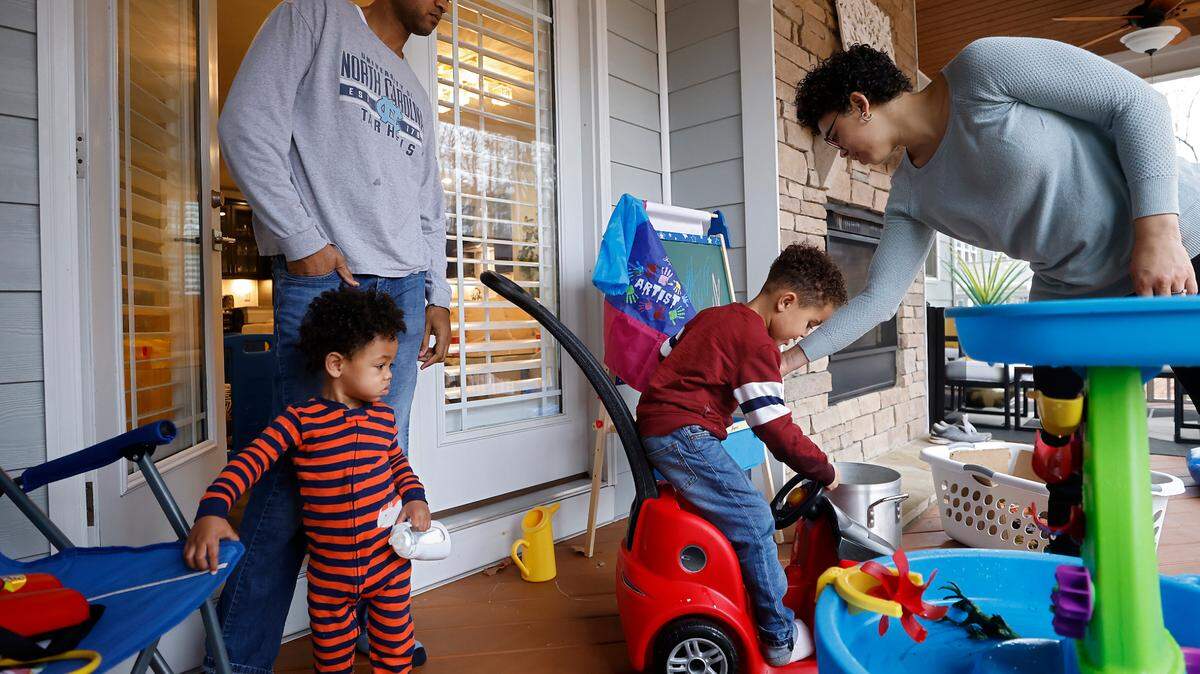 Working parents Brian Wasson and Ashly Gaskin-Wasson of Durham care for their children on Dec. 7, 2022. The couple was working from home while their children, ages 1 and 4, were home from childcare due to symptoms of upper respiratory illness.