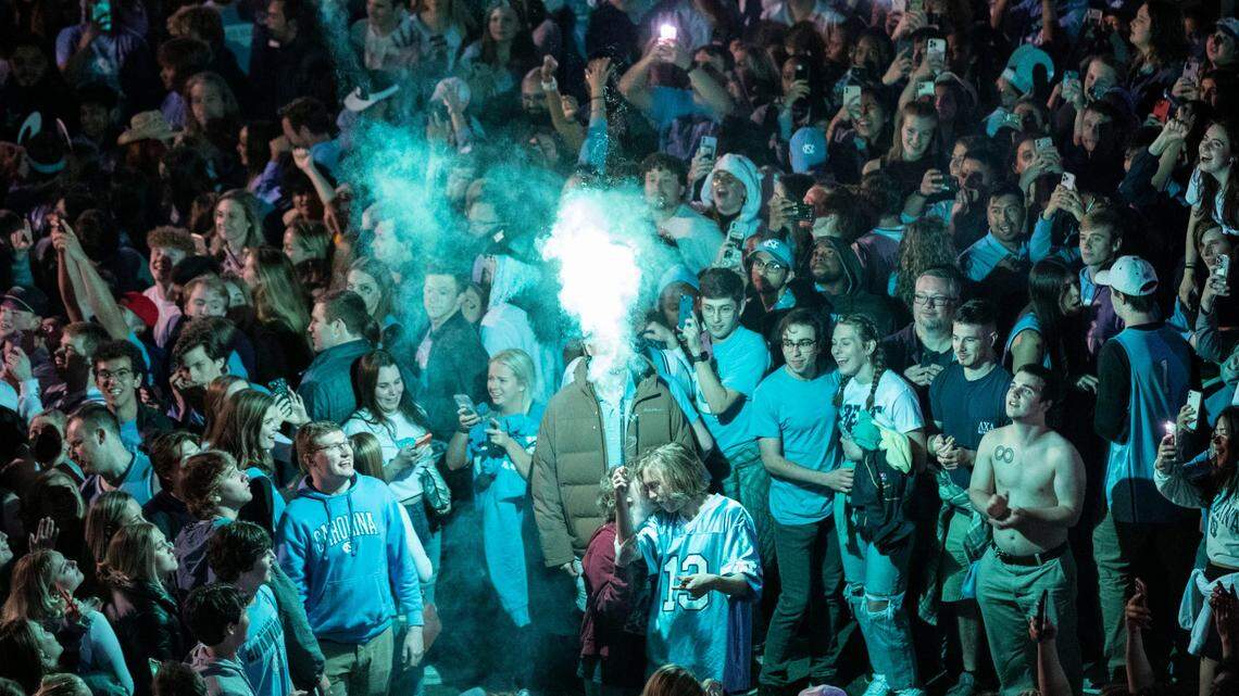A Tar Heel fan launches a firework that lights up a celebrating crowd at the intersection of Franklin and Columbia Streets in Chapel Hill after a historic win against Duke in the Final Four on Saturday, April 2, 2022.