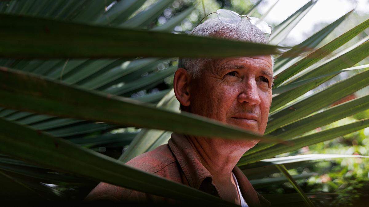 Tony Avent, founder of Plant Delights Nursery and Juniper Level Botanic Garden, is photographed through the leaves of a Sabal brazoriensis at the garden in Raleigh, N.C. on Thursday, May 9, 2024.