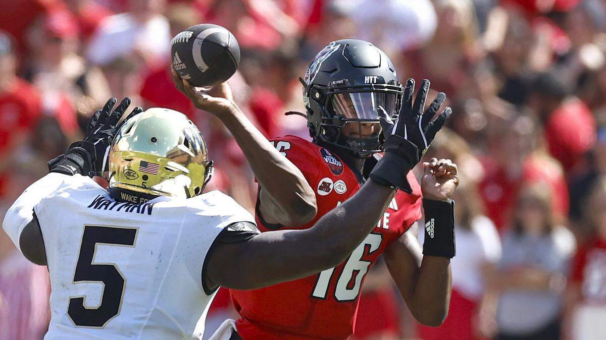 N.C. State quarterback CJ Bailey (16) passes as Wake Forest defensive lineman Kendron Wayman (5) pressures him during the first half of N.C. State’s game against Wake Forest at Carter-Finley Stadium in Raleigh, N.C., Saturday, Oct. 5, 2024.