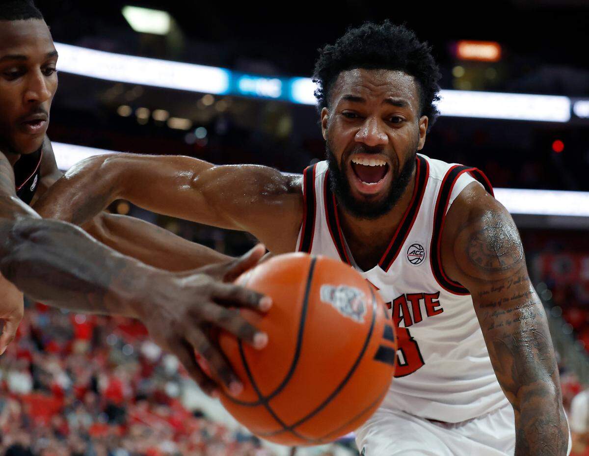 Florida State’s Jamir Watkins and N.C. State’s Dontrez Styles chase after a loose ball during the second half of N.C. State’s 84-74 overtime win on Saturday, Dec. 7, 2024, at Lenovo Center in Raleigh, N.C.
