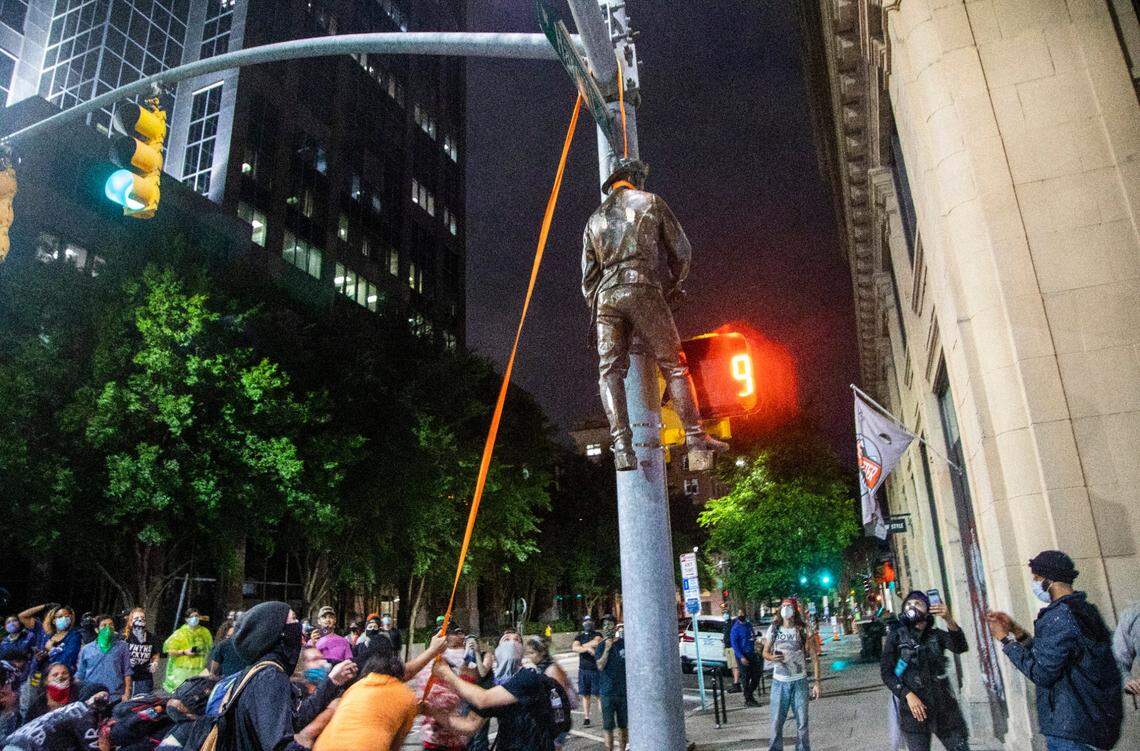 Protesters hang one of the statues pulled from the Confederate monument at the State Capitol at the intersection of Salisbury and Hargett Streets in Raleigh on Juneteenth, Friday, June 19, 2020.
