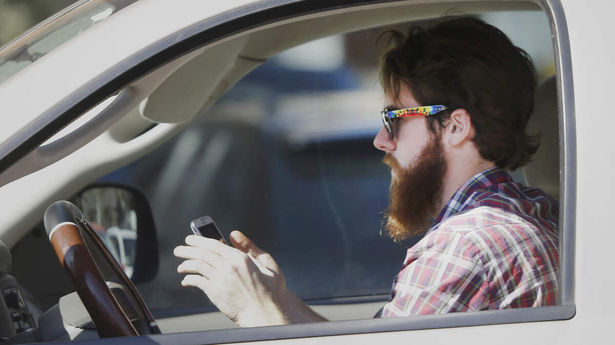 FILE - In this Feb. 26, 2013 file photo, a man uses his cell phone as he drives through traffic in Dallas. In a new survey, 98 percent of motorists who own cellphones and text regularly were aware of the dangers, yet three-quarters of them admit to texting while driving, despite laws against it in some states. Two-thirds said they have read text messages while stopped at a red light or stop sign, while more than a quarter said they have sent texts while driving. (AP Photo/LM Otero)