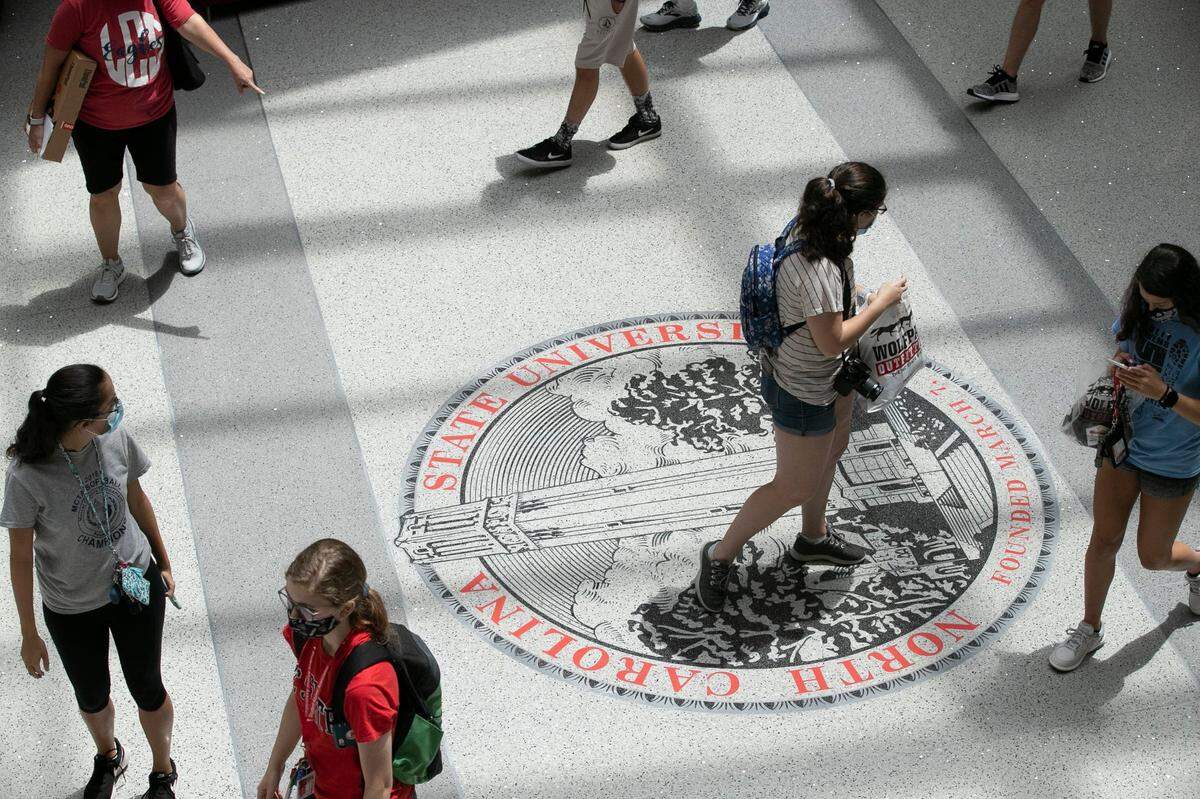 N.C. State University students step across the university logo inside the Talley Student Union on Thursday, August 6, 2020 in Raleigh, N.