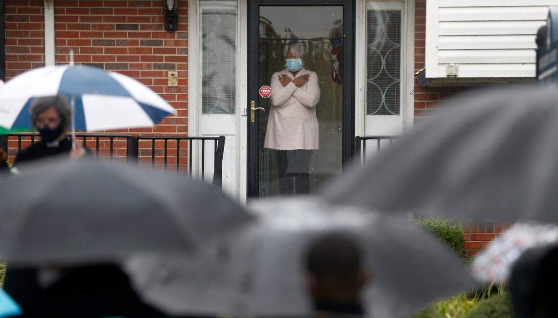 Dr, Christine McPhail, the widow of St. Augustine’s University President Dr. Irving McPhail, watches from the front door of her home as students and faculty pay their respects on Friday, October 16, 2020 in Raleigh, N.C. Nearly 100 participated in a prayer gathering and march to the president’s home to honor Dr. McPhail who died Thursday night due to the COVID-19 virus.