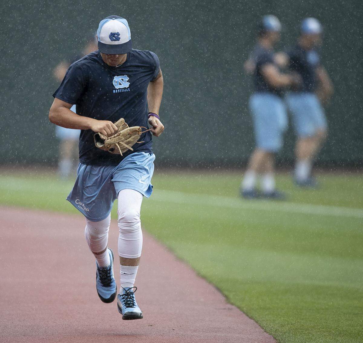 North Carolina pitcher Joey Lancellotti (31) sprints to the dugout to escape a downpour on Friday June 7, 2019 at Bosahmer Stadium in Chapel Hill, N.C. The Tar Heels were forced to move their practice for their NCAA Super Regional game against Auburn indoors after heavy rain moved into the area on Friday afternoon.