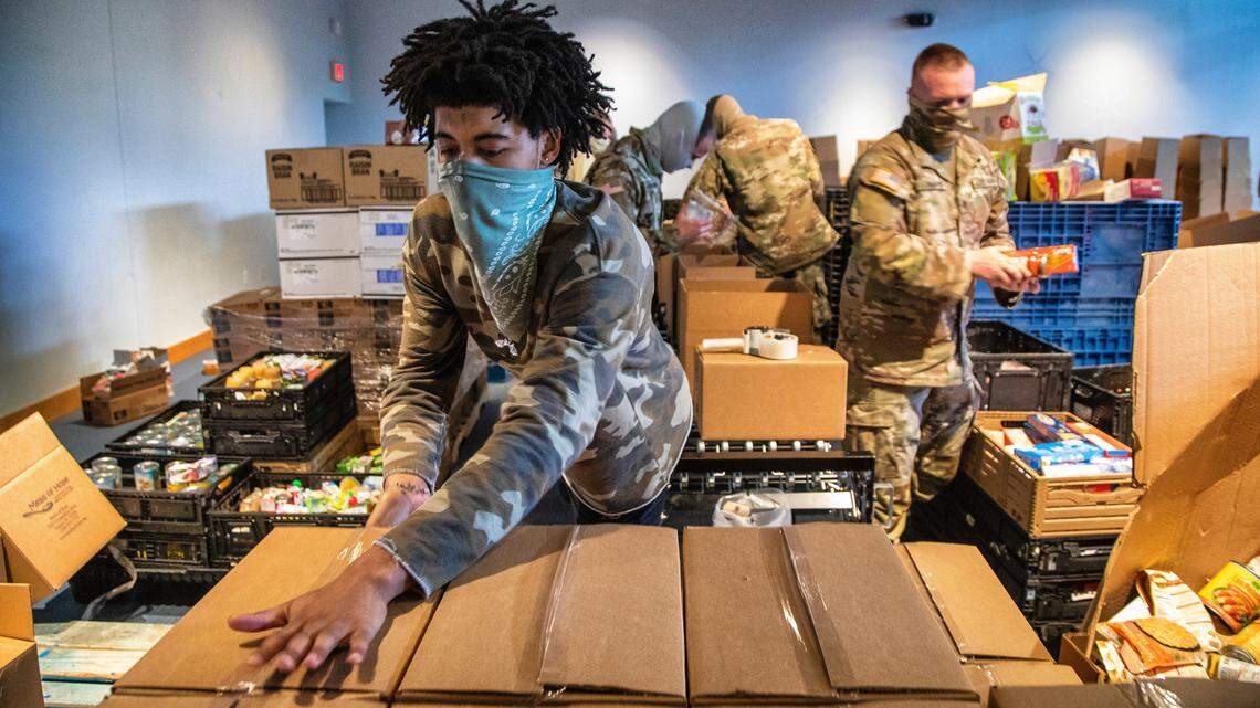 Carter James of the Inter-Faith Food Shuttle, foreground, and NC National Guard troops help package emergency food boxes on May 14, 2020. The boxes were distributed to people in need in Durham, Wake and Chatham counties.