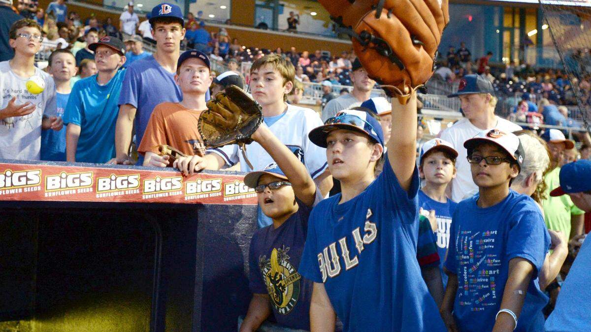 Noah Carter, 12, of Siler City, uses his over sized glove to try to get an autograph after the finish of the Triple A Home Run Derby at the Durham Bulls Athletic Park in 2014. Play Ball With the Bulls invites day campers onto the same field.