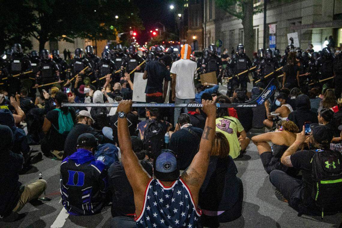 Protesters sit in the street while blocking police in riot gear outside the State Capitol during the second day of protests in Raleigh Sunday night May 31, 2020.