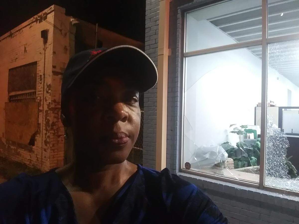Valerie Fields stands in front of her office in downtown Raleigh after bricks were thrown through its windows.