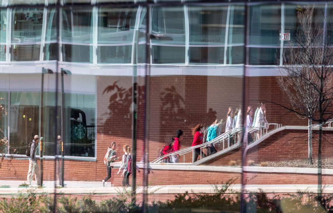 Students are reflected in glass outside the Talley Student Union at N.C. State’s main campus Monday, Feb. 13, 2022.