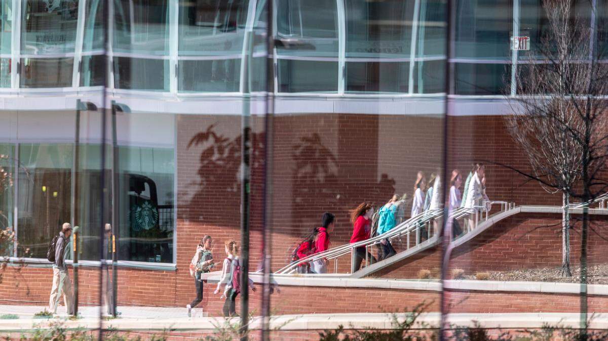 Students are reflected in glass outside the Talley Student Union at N.C. State’s main campus Monday, Feb. 13, 2022.