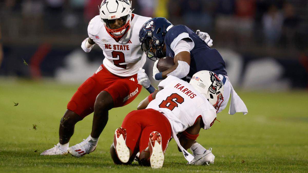 N.C. State’s Jakeen Harris (6) and Jaylon Scott (2) tackle Connecticut running back Devontae Houston (1) during the first half of N.C. State’s game against UConn at Rentschler Field in East Hartford, Conn. Thursday, August 31, 2023.