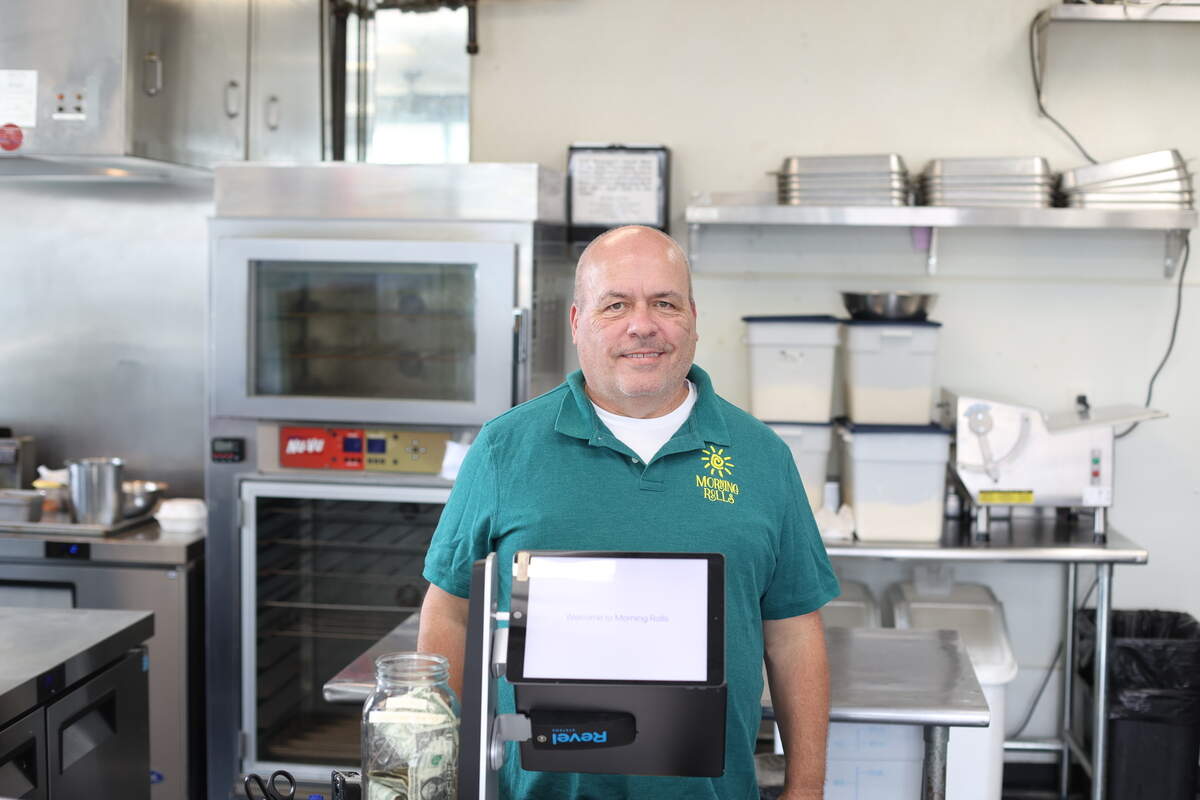 Darryl Fuller smiles behind the counter at his cinnamon roll breakfast restaurant, Morning Rolls in North Raleigh