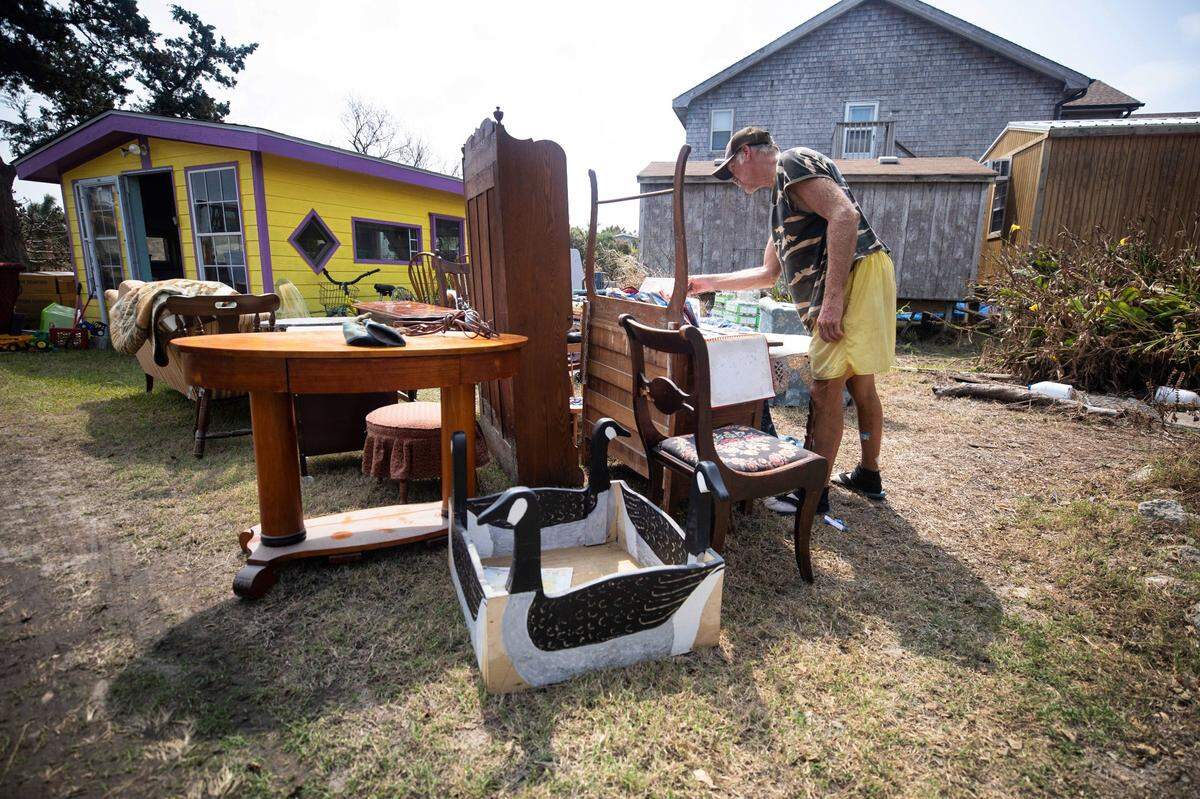 Monroe Gaskill, a native Ocracoke resident, flips through papers and photo albums that belong to his mother, Della, outside her Ocracoke home on Friday Sept. 13, 2019.
