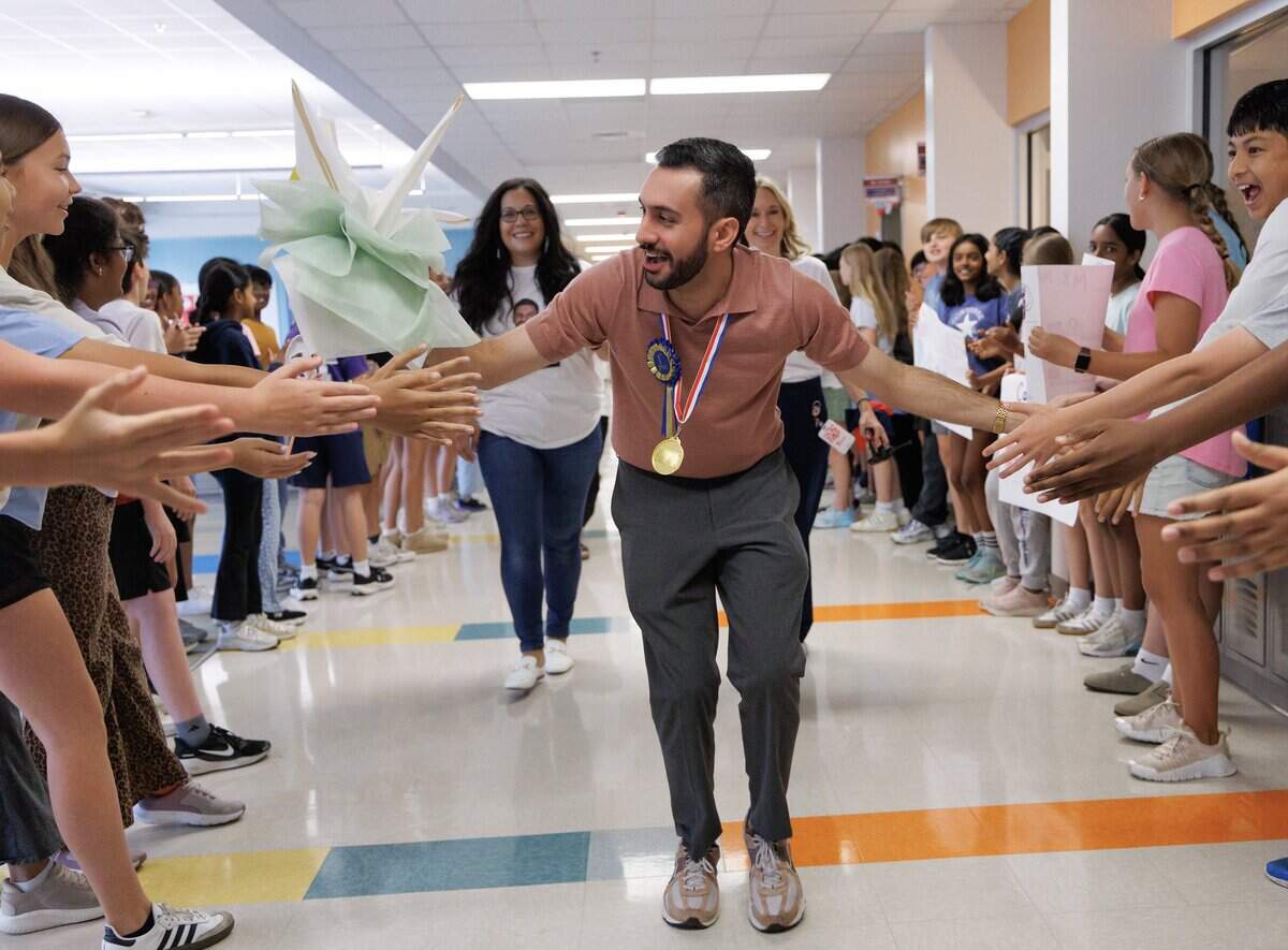 Matin Maani, a seventh-grade social studies teacher at Apex Friendship Middle School, high-fives students during a celebration recognizing him as the 2026 Wake County Teacher of the Year on Thursday, May 21, 2026, in Apex, N.C.