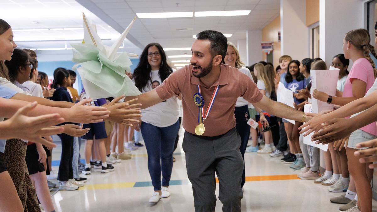 Matin Maani, a seventh-grade social studies teacher at Apex Friendship Middle School, high-fives students during a celebration recognizing him as the 2026 Wake County Teacher of the Year on Thursday, May 21, 2026, in Apex, N.C. 