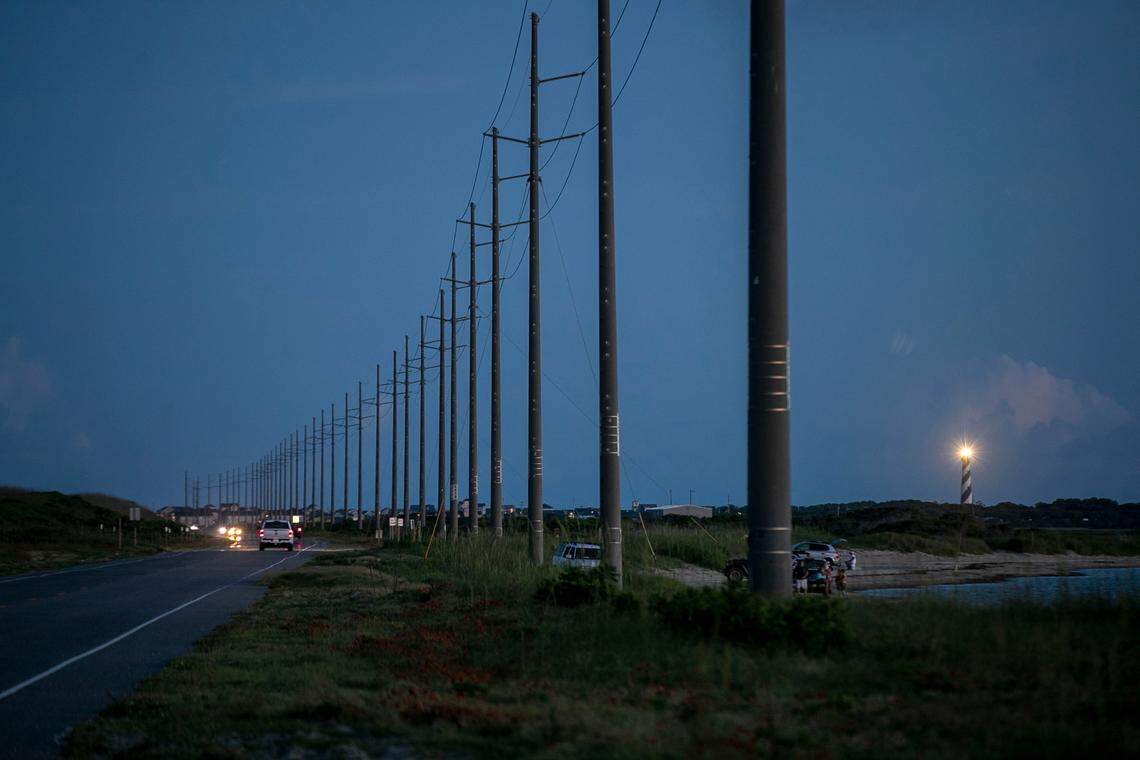 The Cape Hatteras Lighthouse illuminates the evening sky at dusk as traffic moves along NC 12 north of Buxton, N.C. on Tuesday, June 29, 2021.