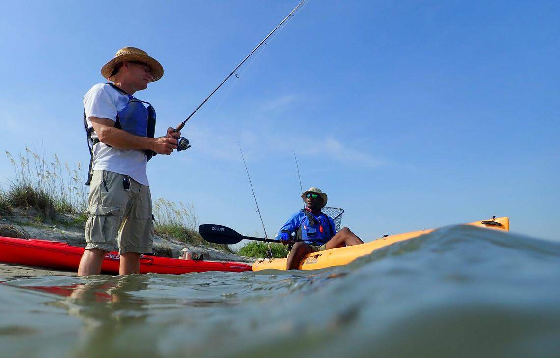 Ken Heil (left) an angler from Maryland, talks with fishing guide Mike Eady while wade fishing in Midway Inlet, Pawleys Island.