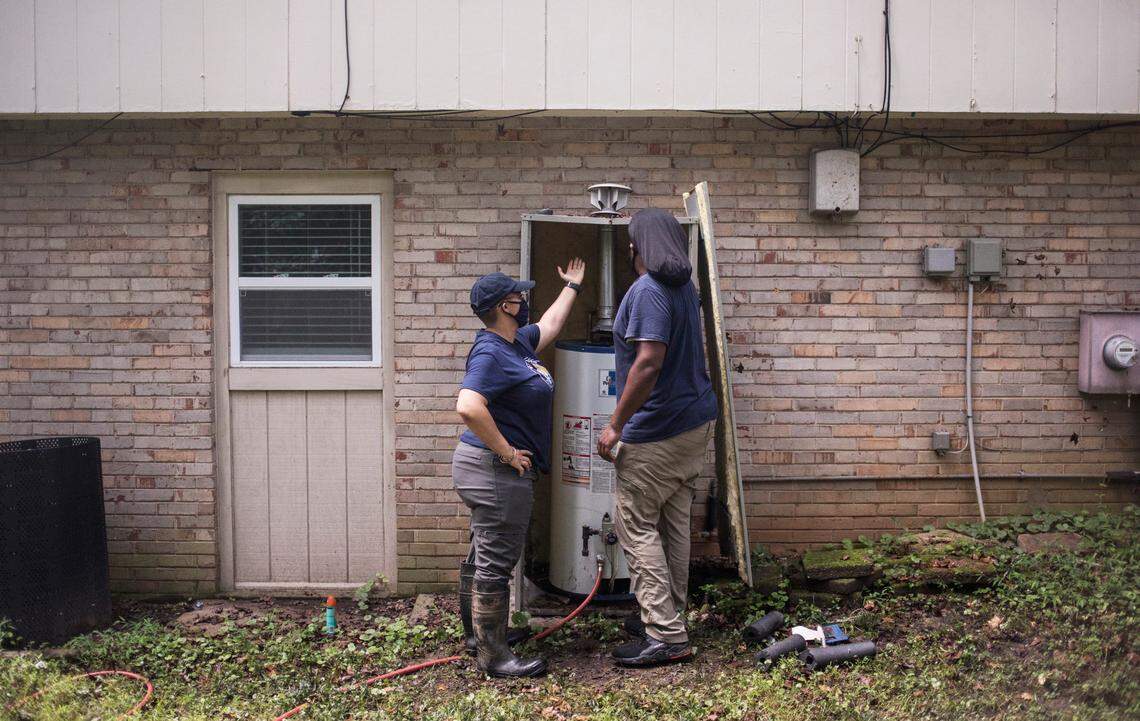 Carrboro Plumbing, Inc. employees Jasmine Jones, left, and Corey Rone, right, assess a broken water heater at a home in Durham, N.C. on Tuesday, Spet. 29, 2020.