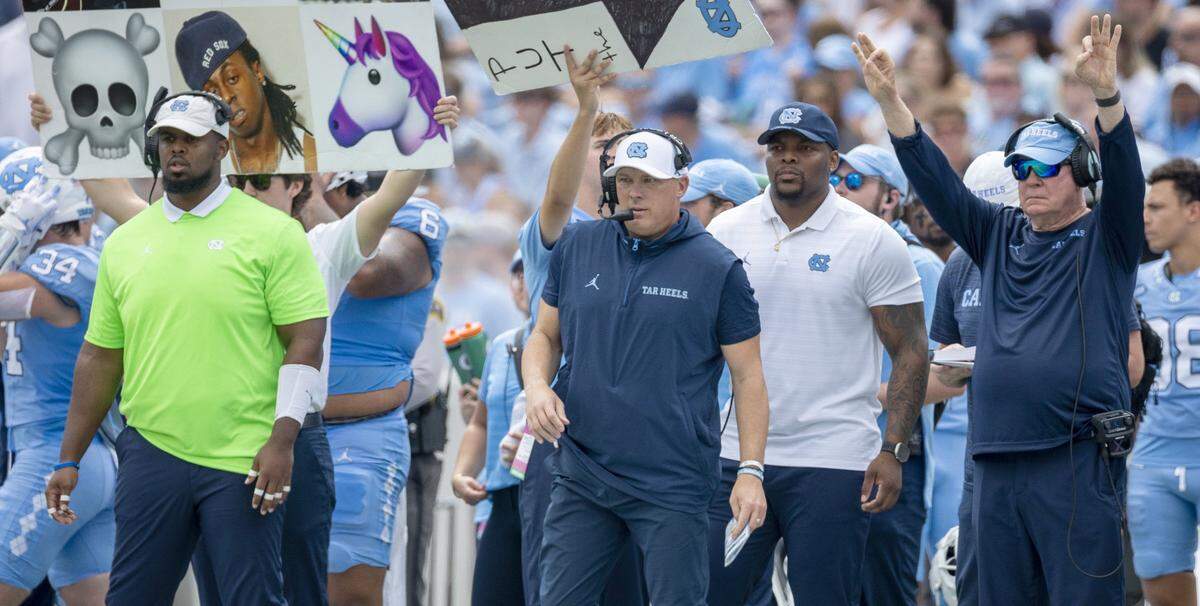 North Carolina defensive coordinator Geoff Collins, center, and head coach Mack Brown, signal to their players in the second quarter against James Madison on Saturday, September 21, 2024 at Kenan Stadium in Chapel Hill, N.C.