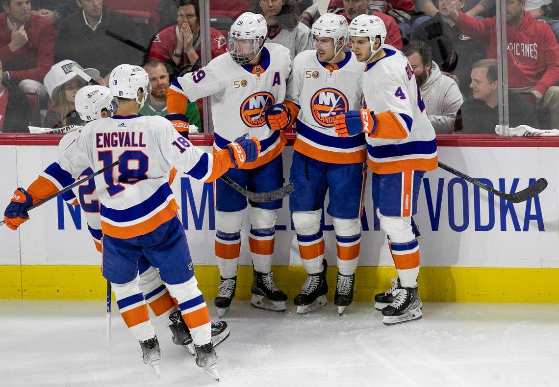 New York Islanders’ Ryan Pulock (6) is surrounded by teammates after scoring on Carolina Hurricanes goalie Antii Raanta (32) in the second period on Monday, April 17, 2023 at PNC Arena in Raleigh, N.C.