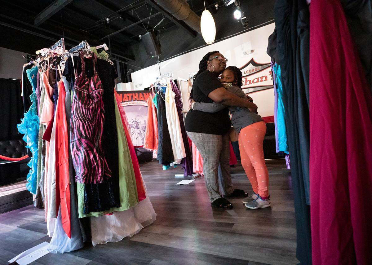 Kiauna Hill pauses to hug McKenzy Lane, 7, during a prom dress drive held by the Hall Foundation at Jonathan’s Sports Lounge & Grill on Wednesday, April 20, 2022, in Raleigh, N.C.