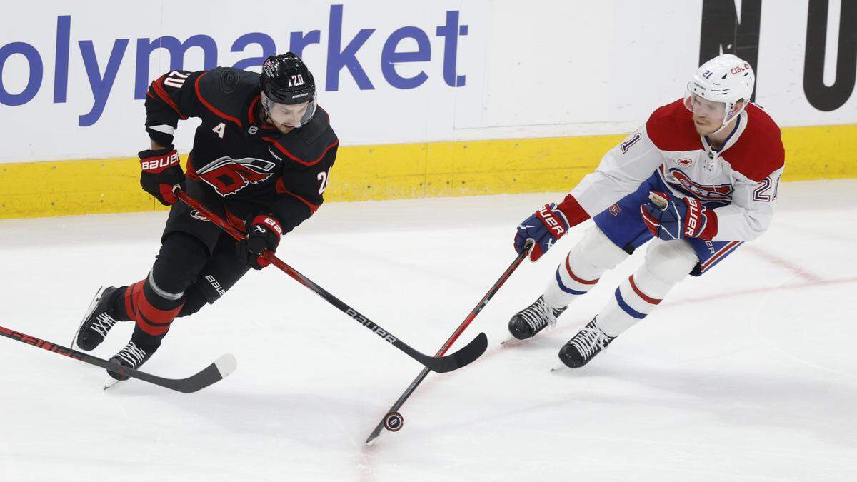 Montréal's Kaiden Guhle (21) knocks the puck away from Carolina's Sebastian Aho (20) during the second period of the Hurricanes’ game against the Canadiens in game one of the Eastern Conference Finals at the Lenovo Center Thursday, May, 21, 2026.